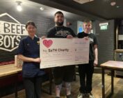 Nurse with Beefy Boys staff holding large charity cheque.