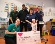 Staff and a child holding a cheque with a representative from Snakebyte.